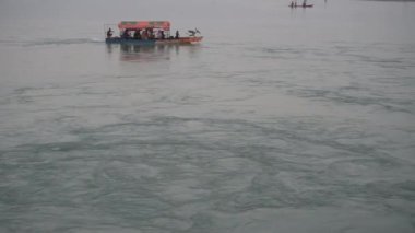 Kuzey Bangladeş 'te rüzgarlı, güneşli bir öğleden sonra, küçük motorlu bir teknede bir aile, günübirlik gezinin tadını çıkarıyor..