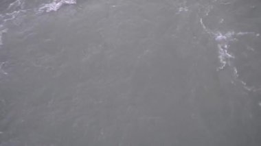 Küçük bir nehirde hızlı akan gri erimiş su..