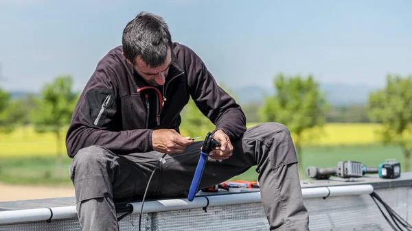 electrical worker preparing electrical connection cables for solar panels with crimper