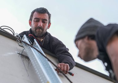 team of electrical engineers install the electrical cables for the autonomous photovoltaic solar panel system. It is installed on a scale and uses a screwdriver to attach the chute that will support electrical cables from solar panels