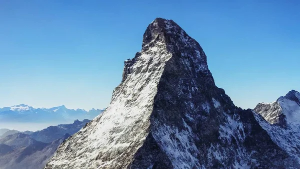 A mountain with a snow covered peak, blue sky in the background, 3d render