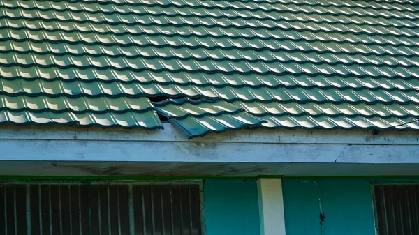 Corrugated roof with a hole. Tin plates on the roof of building.