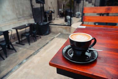 Kahverengi ahşap bir masanın köşesinde fotokopi alanı olan bir kapuçino. Kahve reklamı için harika.