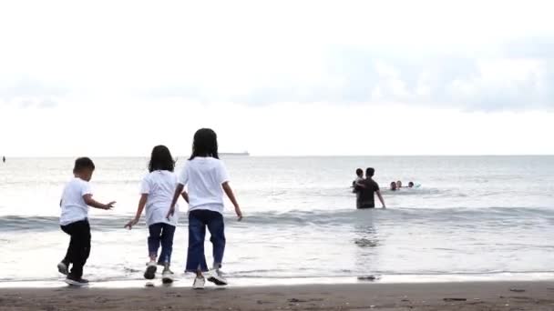 2022年10月29日 Makassar 在海滩享受童年回忆 三个穿着白衣在海滩玩耍的孩子 — 图库视频影像