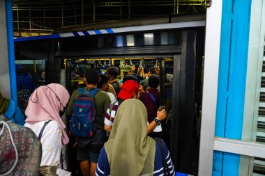 Otobüs yolcuları 1 Haziran 2023 'te Ancol otobüs durağı, Kuzey Jakarta' da otobüse binerken itişip kakışırlar.