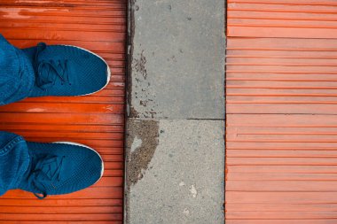 Mavi ayakkabılı ayaklar tahta zeminde duruyor.