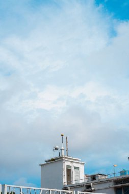 Mavi gökyüzüne karşı beyaz binanın çatısına çıkıyor. Portre fotoğrafı