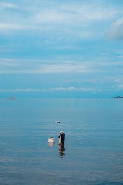 Yaşlı balıkçılar sahilde ağları ve mantar kutularıyla balık arıyorlar. Portre fotoğrafı
