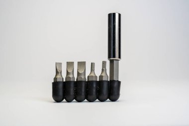 Metal cıvata aleti seti çeşitli boyutlarda. Farklı türde tornavida parçaları. Bulanık beyaz arkaplanda değiştirilebilir metal araçları yığını