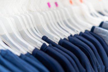 Giysilerin mağaza rafında asılı durması.