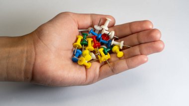 Beyaz arkaplandaki bir avuç renkli itme iğnesi