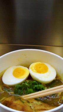 Lezzetli Ramen Çorbası 'nın Dikey Yavaş Çekimi Haşlanmış Yumurta ve Taze Bitkiler
