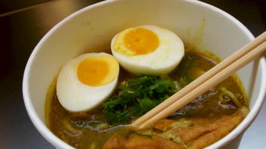 Kaynamış yumurta ve taze bitkilerle Ramen Çorbası 'nın yavaş çekimleri.