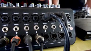 Ses mühendisliği, müzik üretimi ve profesyonel bir stüdyoda veya canlı etkinlik ortamında ses mühendisliği, müzik üretimi ve kayıt ayarları için ideal olan giriş ve bağlı kabloları gösteren bir ses karıştırıcı panelinin yakın görüntüsü