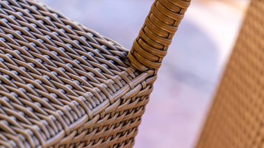 Sıcak, bulanık bir açık hava ortamında dokunmuş hasır bir sandalyenin detaylı görüntüsü mobilya tasarımı kavramları için harika bir doku ve işçiliği gösteriyor..