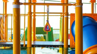 İçinde üçgen halkalar ve mavi slayt bulunan renkli bir oyun alanı çocukların aktiviteleri ve eğlence içeriği için canlı bir sahne yaratıyor..