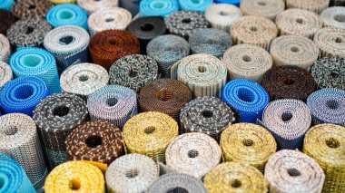 Çeşitli desenli tekstil ruloları moda veya tasarım projelerinde kullanmak için ilginç bir doku arkaplanı oluşturur.