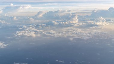 Pofuduk beyaz bulutlar, bir uçak penceresinden bakıldığında seyahat ve havacılık ile ilgili konular için ideal sakin ve hayranlık uyandırıcı bir atmosfer yaratıyor..