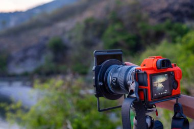 Bir fotoğrafçı profesyonel bir DSLR kamera ve lens filtresi kullanarak açık havada fotoğraf çekiyor. Bu resim fotoğraf ekipmanları ve açık hava yaşam tarzı projeleri için harikadır..