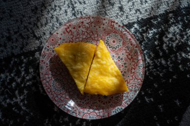 Dekoratif bir tabakta sunulan iki dilim sarı pasta. Güneş ışığı gölge yaratıyor. Yemek blogları ve mutfak tasarımları için ideal..