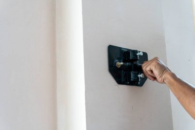 Duvara monte edilmiş siyah duvar montaj donanımı üzerindeki bir sürgüyü sıkmak ev geliştirme veya DIY içeriği için kullanışlıdır.