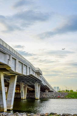 Bulutlu bir gökyüzünün altında uzanan beton bir köprüye bakıyorum, uzak bir düzlemde, kentsel altyapı görselleri için mükemmel..