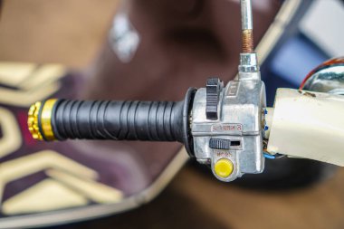 Siyah kauçuk kavrama ve klasik krom dönüş sinyal montajı içeren bir motorsiklet gidonunun yakın çekimi, ulaşım veya klasik motosiklet içeriği için mükemmel.