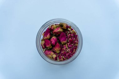 Kurumuş gül tomurcukları ve taç yapraklarıyla dolu temiz bir kavanozun yukarıdan çekimleri bitkisel çaya uygun narin bir çiçek sergisi oluşturuyor..