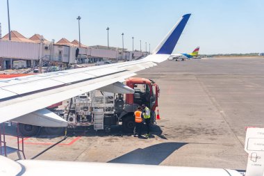 Uçak gün boyunca havaalanında mürettebat tarafından yakıt ikmali yapılıyor. Terminal görünür durumda. Seyahat veya havacılık içeriği kullanılıyor..