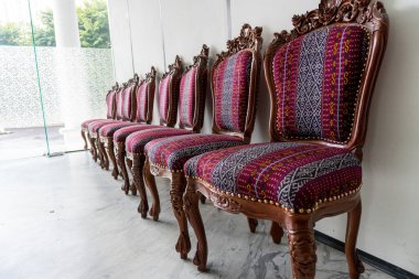 Süslü ahşap sandalyeler desenli kumaşla süslenir. Mekana klasik tarz katar ve iç tasarım için ilham verir..