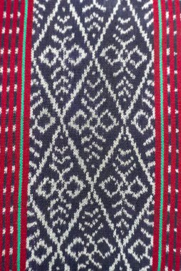 Yakın plan, arka plan veya tasarımlar için ideal kırmızı ve yeşil, geometrik desenli ve renkli kenarlı bir tekstil gösterir.