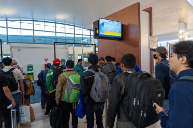 Yolcular bir havaalanının kapısında kuyruğa girdiler. Seyahat ve ulaşımı resmetmek için ortak bir sahne olan uçağa binmeyi bekliyorlar..