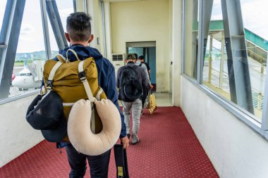 Bagajı olan insanlar, seyahat ve ulaşım için mükemmel olan bir yolculuk için jet köprüsüne doğru yürüyorlar..