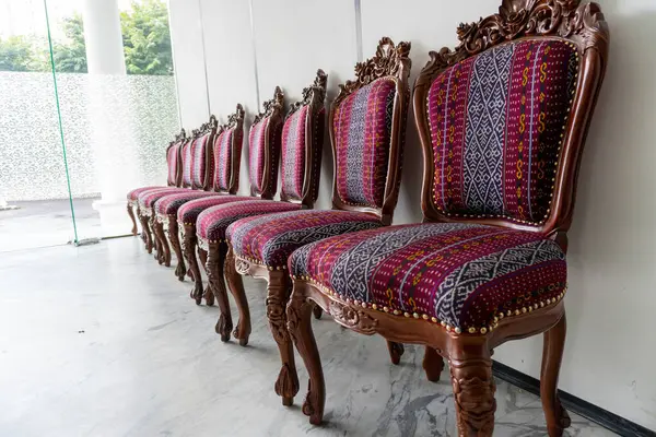 Süslü ahşap sandalyeler desenli kumaşla süslenir. Mekana klasik tarz katar ve iç tasarım için ilham verir..