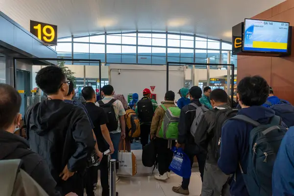 Bir grup yolcu, havaalanı kapısında sırt çantalarıyla sıraya girerler. Seyahat ve ulaşım temalarını kullanın..