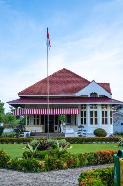 Ulusal kırmızı ve beyaz bayrak mavi gökyüzünün altında Gedung Juang Tambun 'un önünde dalgalanıyor seyahat ve tarih projeleri için harika.