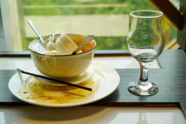 Yemek yedikten sonra boş bir bardağın yanına konmuş tabak ve kase yığını yaşam tarzı ya da restoran sahneleri öneriyor..