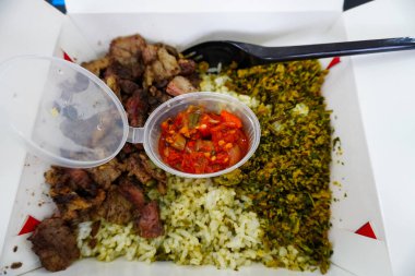 Bir pirinç tabağında ızgara et, sambal biber sosu ve yemek blogları ve mutfak sunumları için mükemmel bir paket servis kutusunda sebze sebzeleri bulunur..