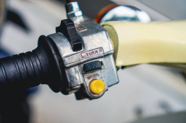 Yakın plan, dönüş sinyalleri ve korna düğmelerini gösteren eski bir scooter 'ın gidon kontrollerini yakalar. Araç ve ulaşım temaları için mükemmel.