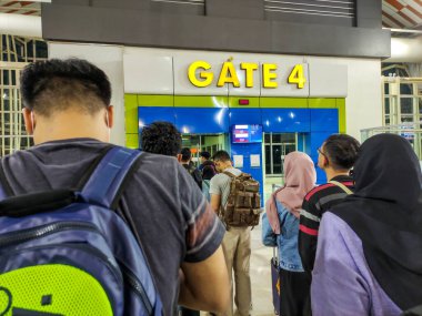 Sırt çantalı insanlar tren istasyonunun 4. kapısında sıraya girerler. Seyahat ve ulaşım kavramları burada iyi temsil edilir..