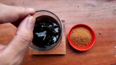 Tahta masa üstünde siyah kahveyle esmer şekeri karıştırmak