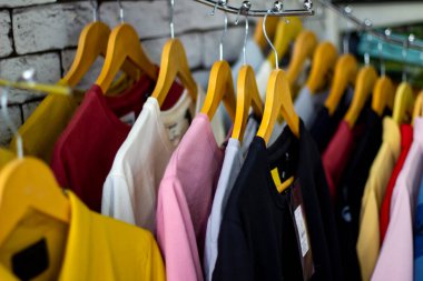 Pamuk ve spor tişörtleri elbise mağazasının duvarındaki askılarda asılı. Saha derinliğine odaklanmış alçak açı manzaralı.