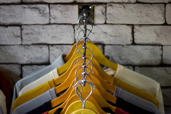 Cotton and sports t-shirts hung on wall hanger racks inside a clothes shop low angle view with the focused depth of field