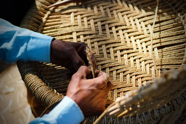 stock image Skilled craftsman working manually a detailed bamboo wood armchair with his fingers and tools