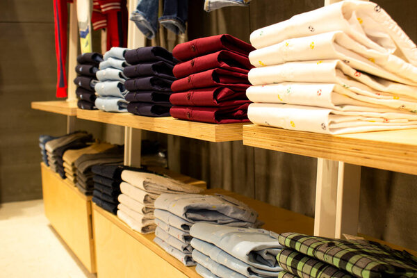 Shirt and pant hanging on hangers on a clothing rack and arranged in shelf in a modern clothe store