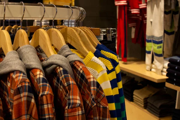 Shirt and pant hanging on hangers on a clothing rack and arranged in shelf in a modern clothe store