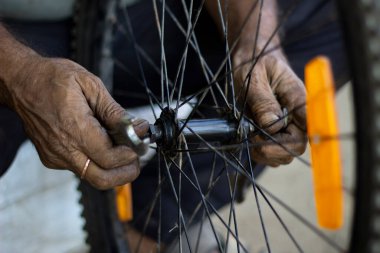 Motosiklet lastiği üzerinde çalışan yaşlı adam, bir serviste yakın görüşlü, parmaklarını kullanıyor.