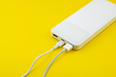 Beyaz güç bankası usb a ve c kablosu sarı arkaplanda izole edildi. 