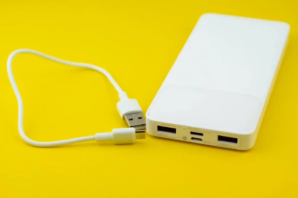 Beyaz güç bankası usb a ve c kablosu sarı arkaplanda izole edildi. 