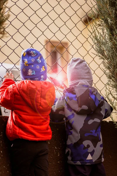 Çocuklar çitin arkasındaki gümüş arabaya bakıyor. çocukluk rüyaları konsepti